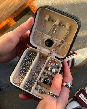 Hand holding a jewelry case with necklaces and rings